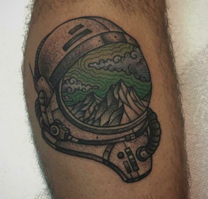Mountains reflection in astronaut's helmet tattoo