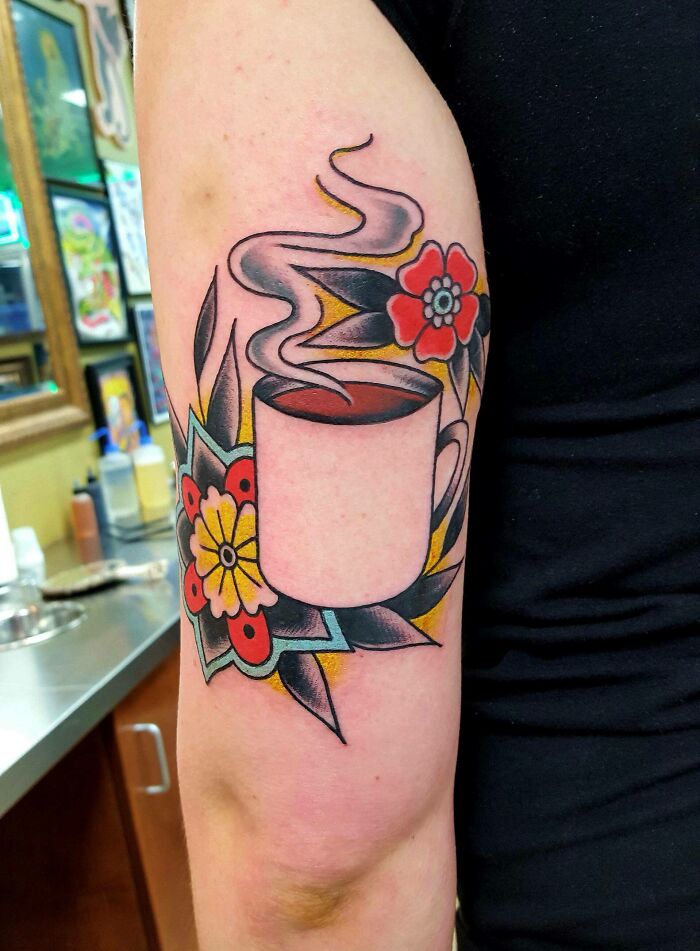 Arm tattoo featuring vibrant flowers and a steaming coffee cup, showcasing elegance and beauty.