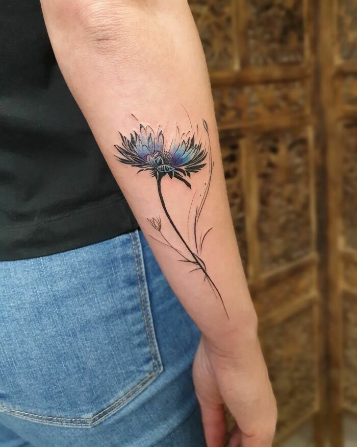 Delicate flower tattoo on forearm showcasing elegance and beauty with vibrant colors.