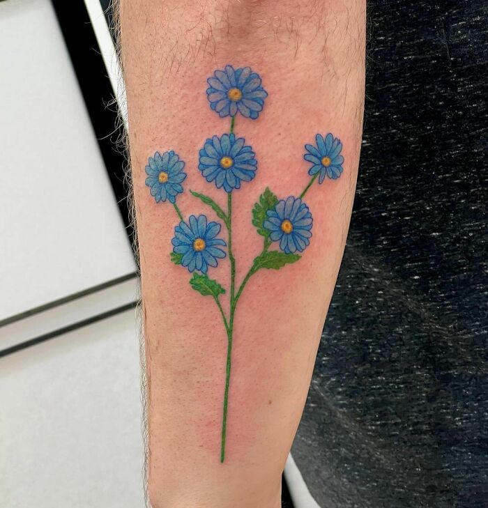 Blue flower tattoo on forearm, showcasing elegant and beautiful floral design.