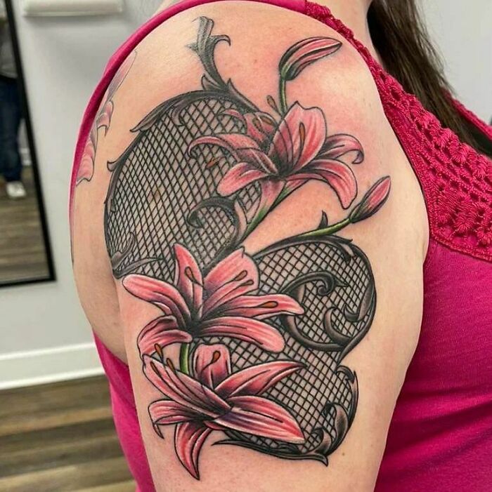 Elegant flower tattoo featuring pink lilies with black lace pattern on upper arm.