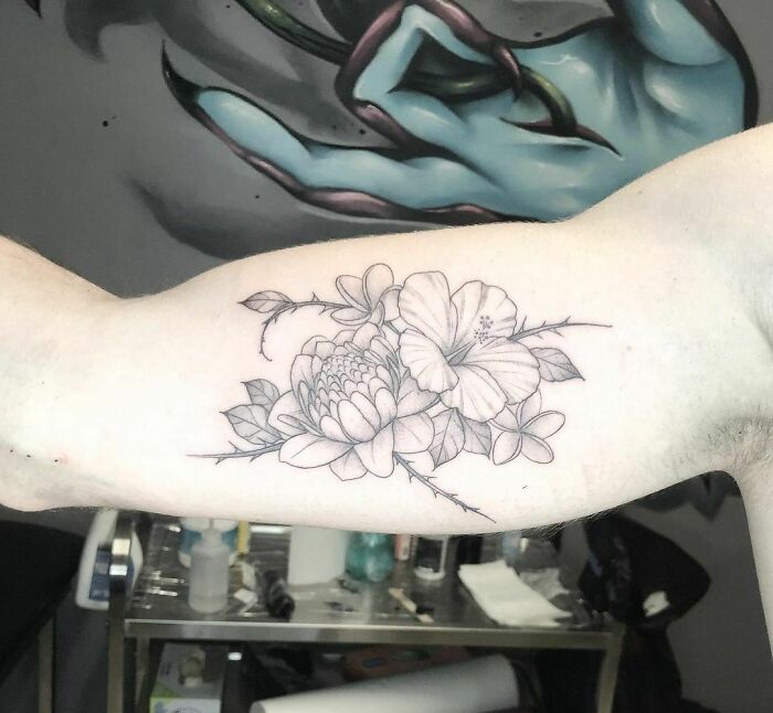 Elegant flower tattoo design on a person's arm, showcasing detailed blooms and leaves.