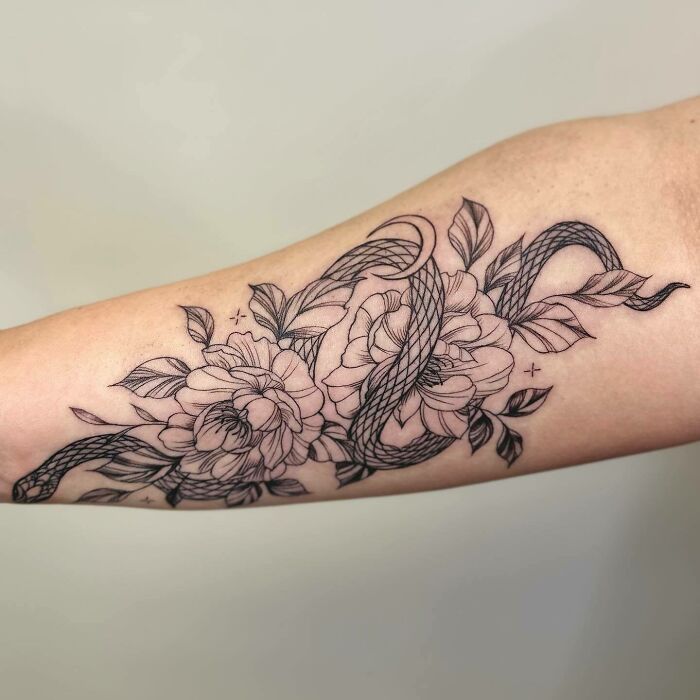 Flower tattoo design featuring intricate blossoms and flowing ribbons on forearm, showcasing elegance and beauty.