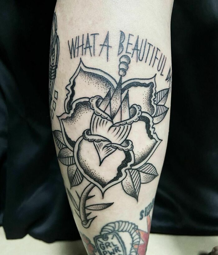 Abstract flower tattoo with geometric shapes and "What a beautiful day" text, showcasing elegance and beauty.