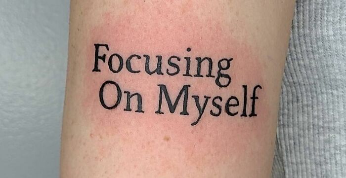 Self-love tattoo on arm with "Focusing On Myself" text in black ink.