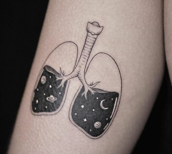 Tattoo of lungs filled with cosmic designs, symbolizing self-love and uniqueness.