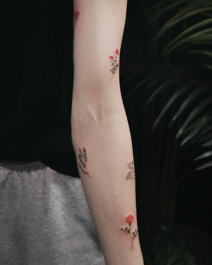 Elegant arm adorned with delicate flower tattoos, radiating beauty and sophistication.