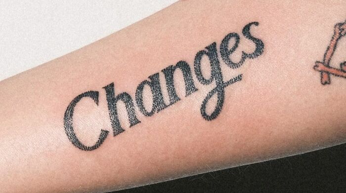 Tattoo of the word "Changes" on a forearm, representing self-love and personal growth.