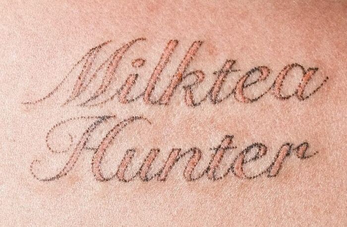 Close-up of "Milktea Hunter" tattoo in cursive, representing self-love and empowerment.