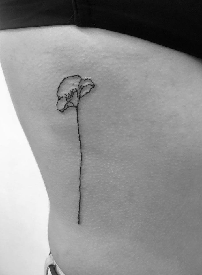 Minimalist flower tattoo design on skin, emphasizing elegance and beauty.
