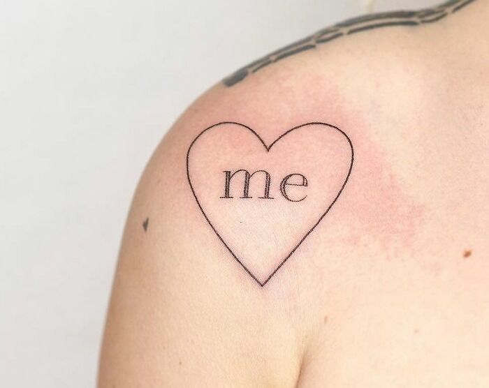 Heart-shaped self-love tattoo on a shoulder with the word "me" inside, symbolizing empowerment and self-appreciation.