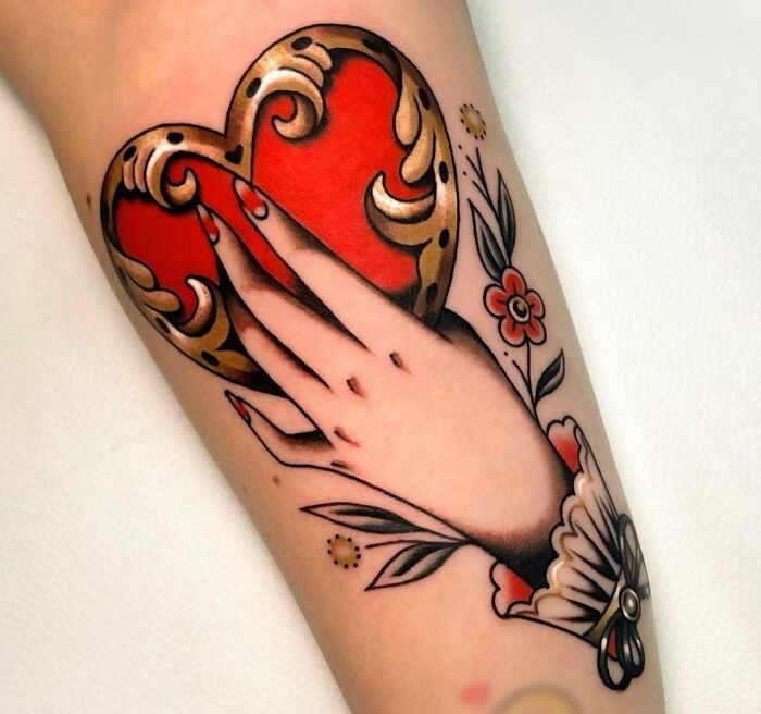 Golden heart with females' hand tattoo 