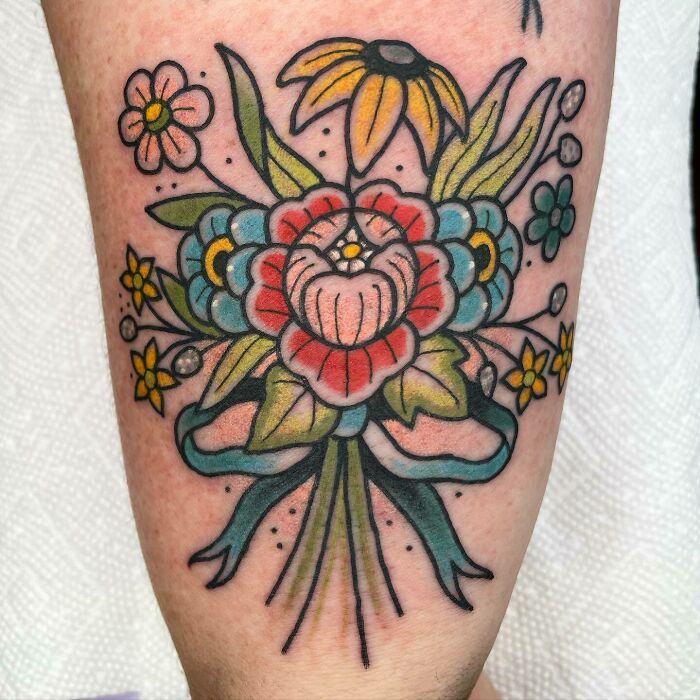 Vibrant flower tattoo showcasing elegance and beauty with colorful blooms and leaves.