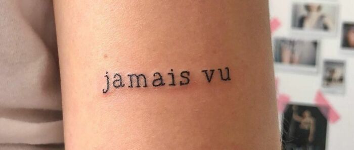 Minimalist self-love tattoo with the phrase "jamais vu" inked in small black letters on a person's arm.