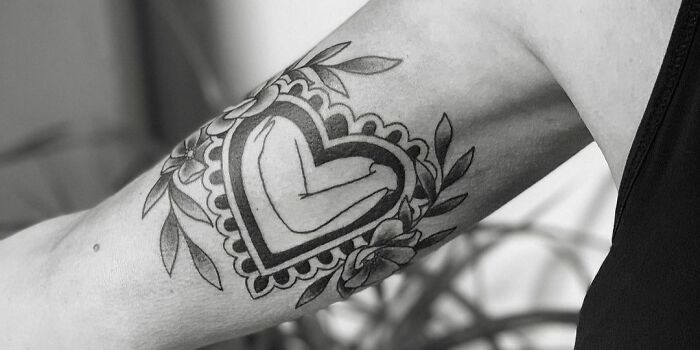 Arm tattoo featuring a heart with floral details, symbolizing self-love.