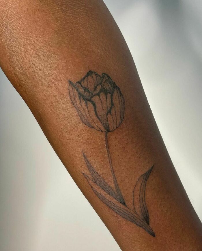 Elegant flower tattoo on forearm showcasing delicate linework and beauty.