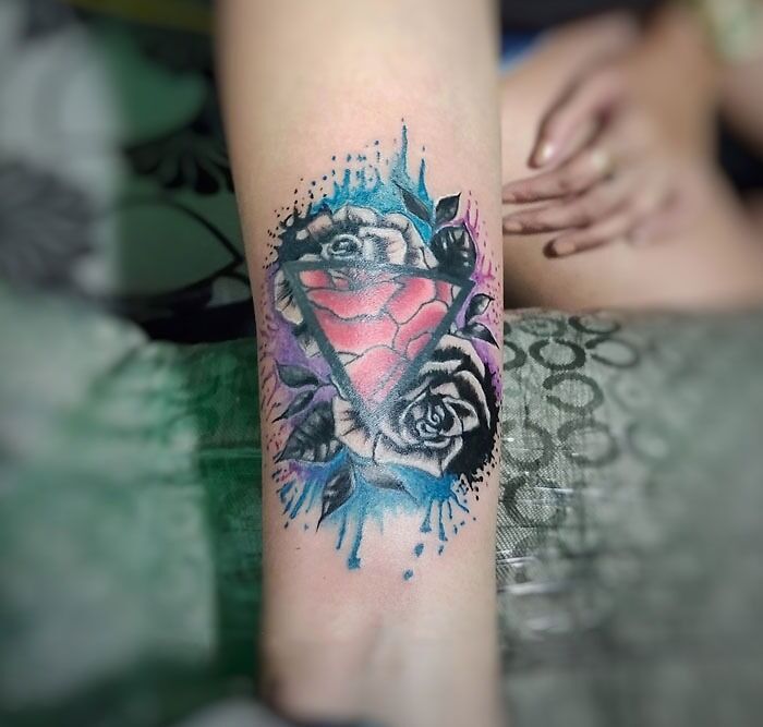 Colorful geometric tattoo with roses on a forearm, showcasing creativity.
