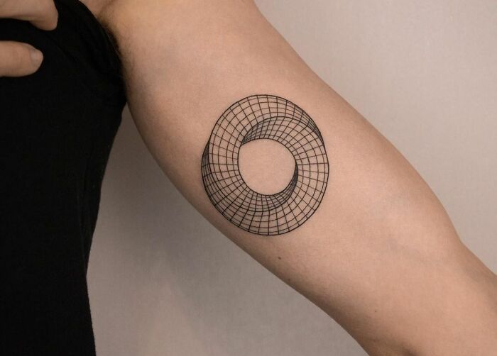Geometric tattoo on forearm featuring a complex circular design with intricate line patterns.
