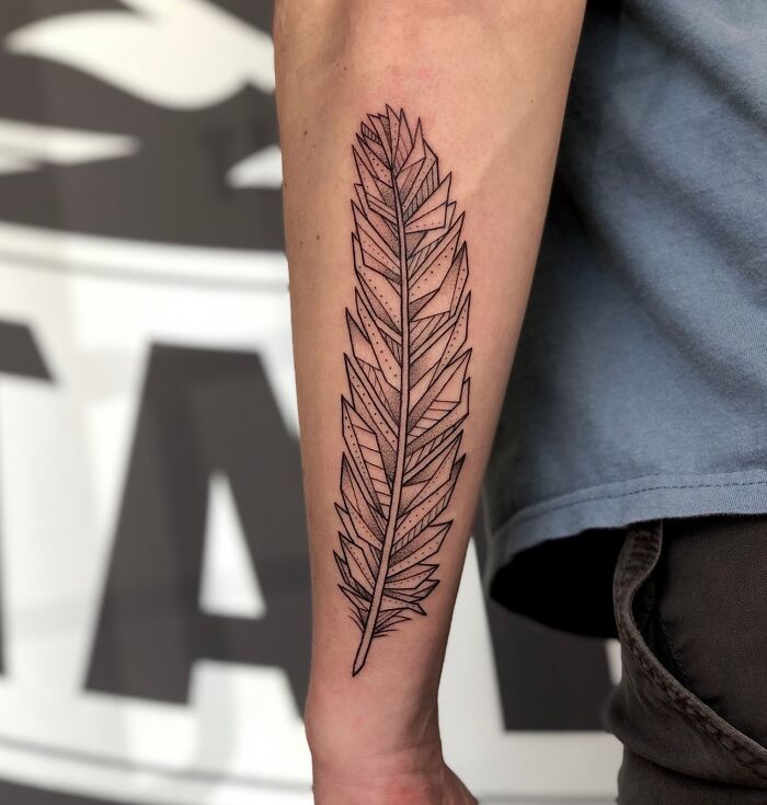 Geometric tattoo of a stylized leaf on a person's forearm, showcasing intricate linework and design.