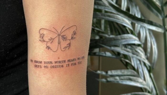 Self-love tattoo with a butterfly design and motivational text on a person's arm.