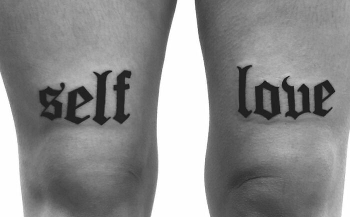 Self-love tattoo in bold black letters on the back of someone's thighs.