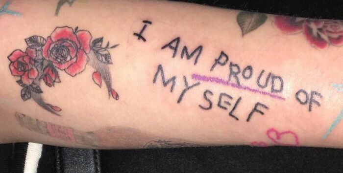 Self-love tattoo with "I am proud of myself" text and red roses on skin.