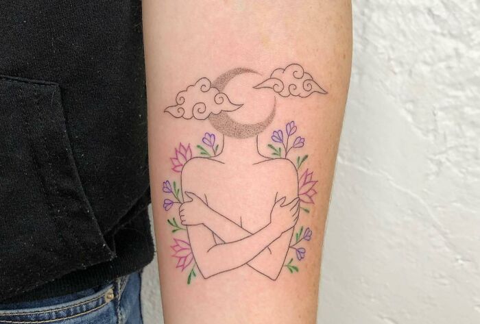 human huggin himself with flowers and moon head arm tattoo