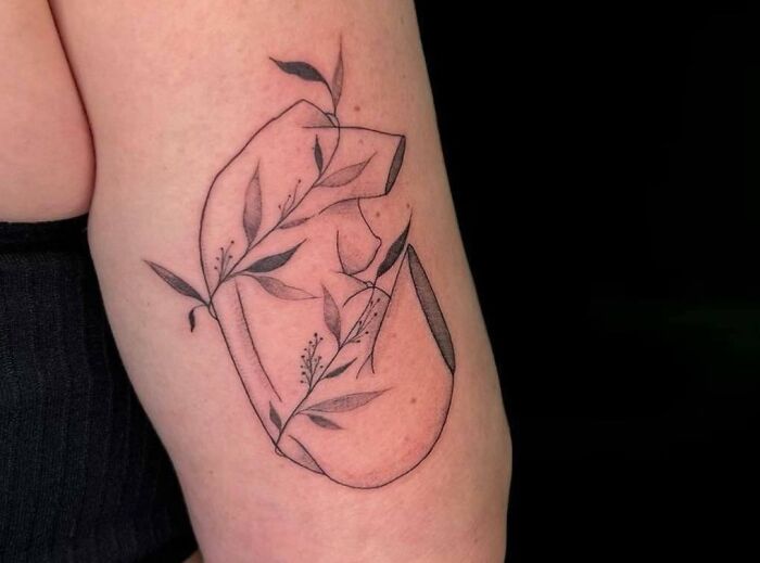 A delicate self-love tattoo featuring abstract lines and botanical elements on an arm.