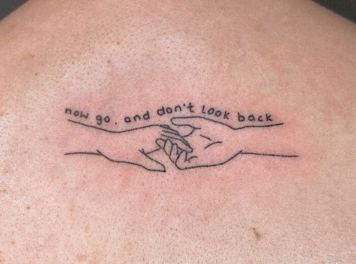 Minimalist self-love tattoo featuring two hands with the phrase "now go, and don't look back."