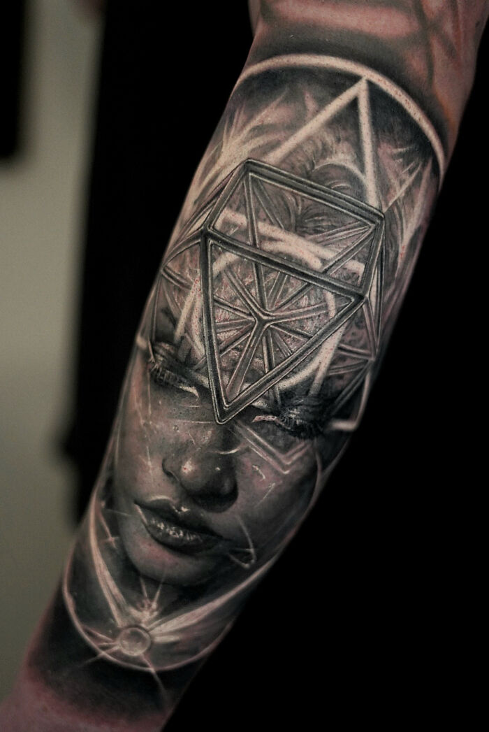 Realistic tattoo on forearm depicting a geometric design over a detailed woman's face.
