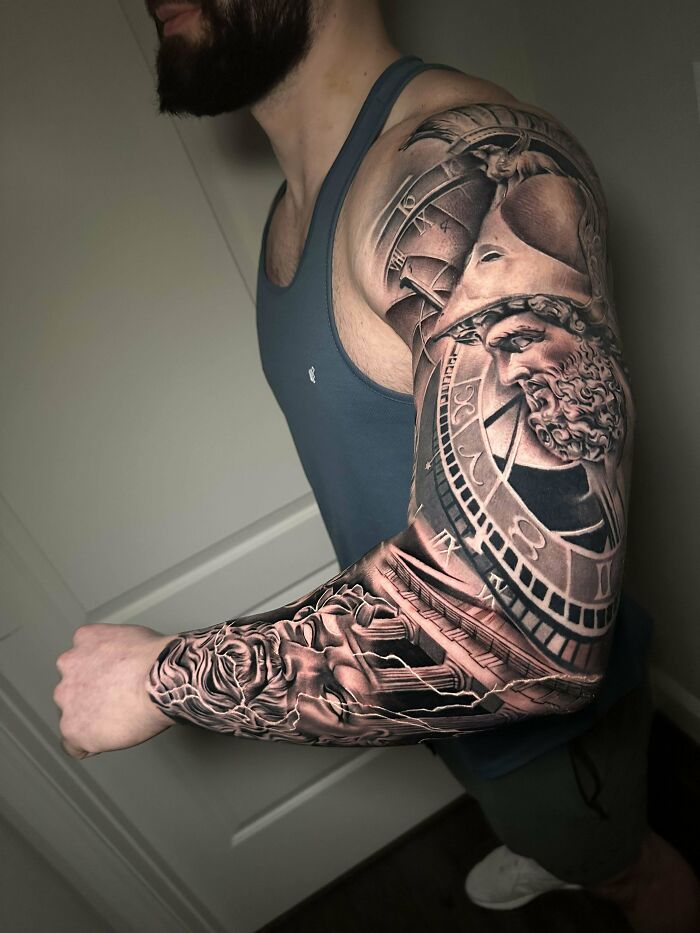 Man showcasing a super realistic sleeve tattoo featuring intricate designs and a classical figure.