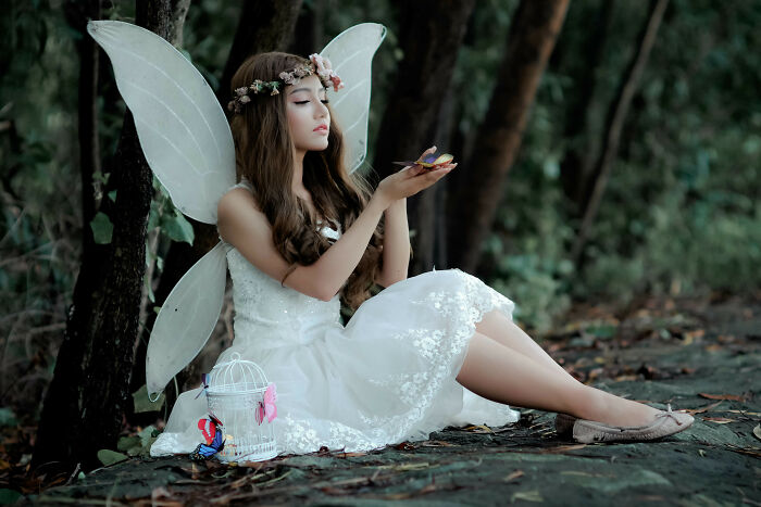 a girl with wings on her back holding butterfly in her hands