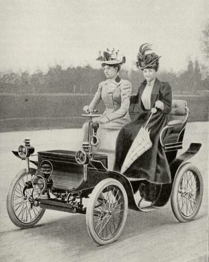 Dos señoras montan en un coche antiguo, 1900