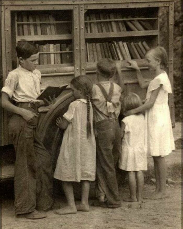 Niños descalzos en una carreta ambulante de libros en los Apalaches