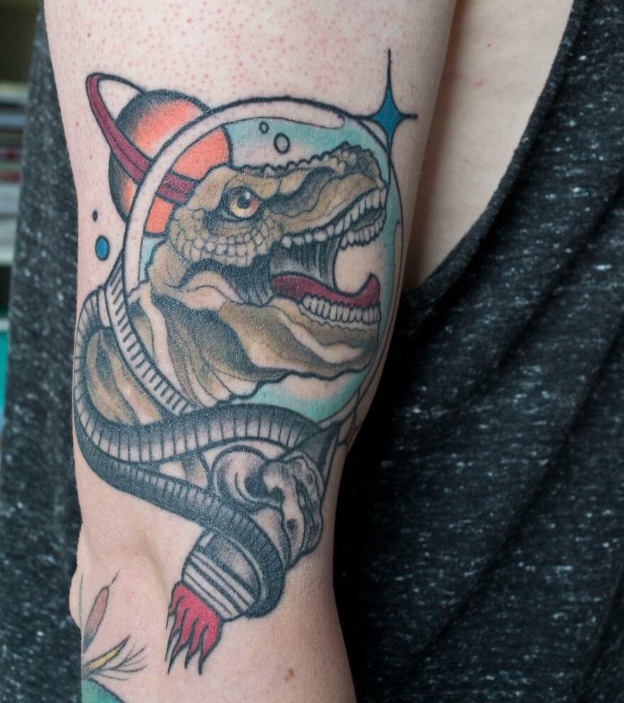 Space dinosaur arm tattoo