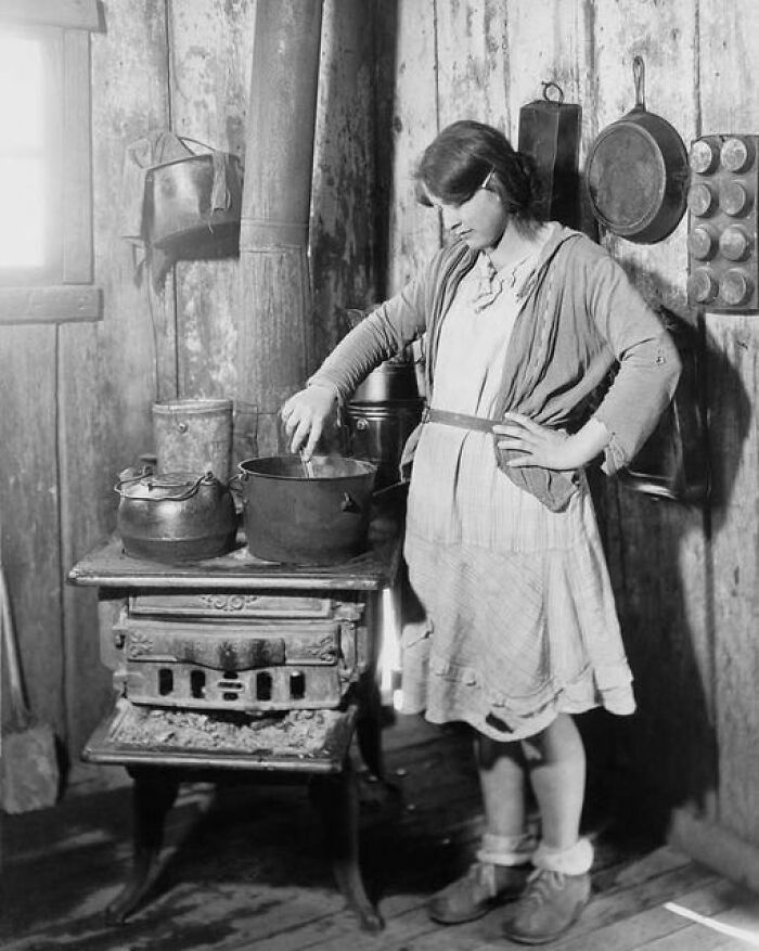 La hija adolescente de un empobrecido granjero de Arkansas cocinando en un viejo fogón mientras su madre estaba en un sanatorio para tuberculosos durante la Gran Depresión. Foto de la Cruz Roja alrededor de 1930