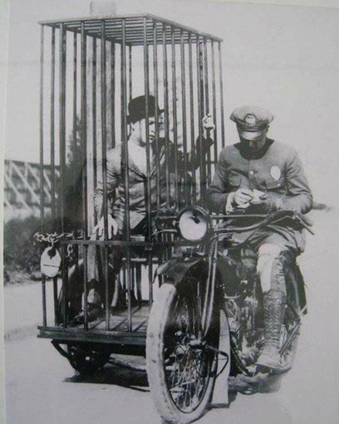 Un agente de policía en una Harley-Davidson transporta a un preso en una celda móvil (1921)