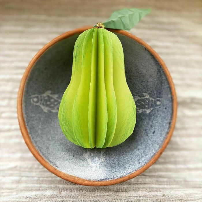 a green paper pear on a bowl