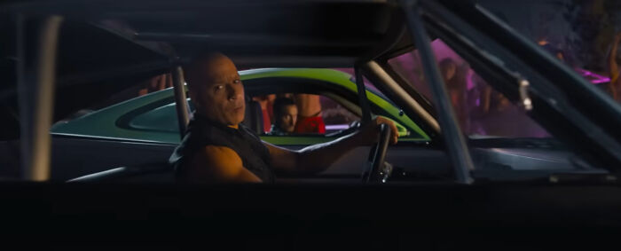 Actor driving a car in a night scene, representing one of the highest-paid actors in an action movie setting.