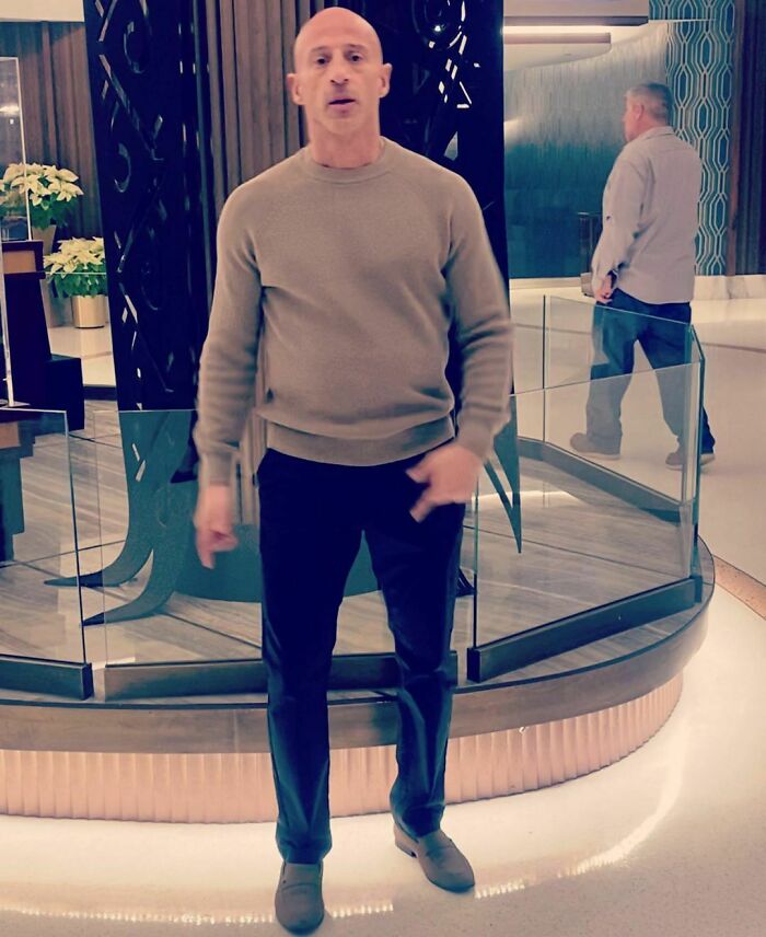 Man in a beige sweater standing in a modern interior, related to celebrities who went to jail for crimes.