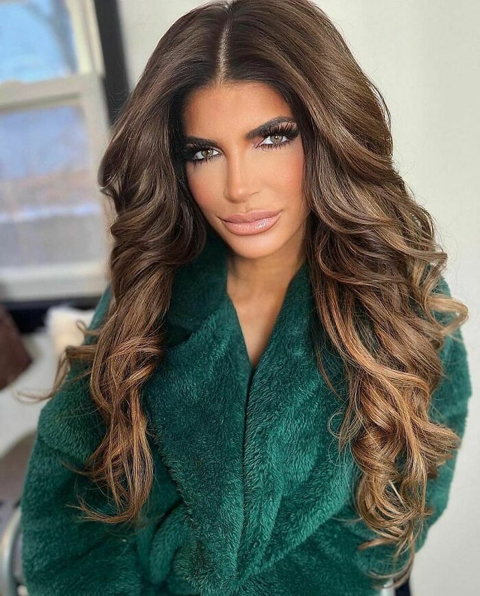 Celebrity in a green robe with long, styled hair.
