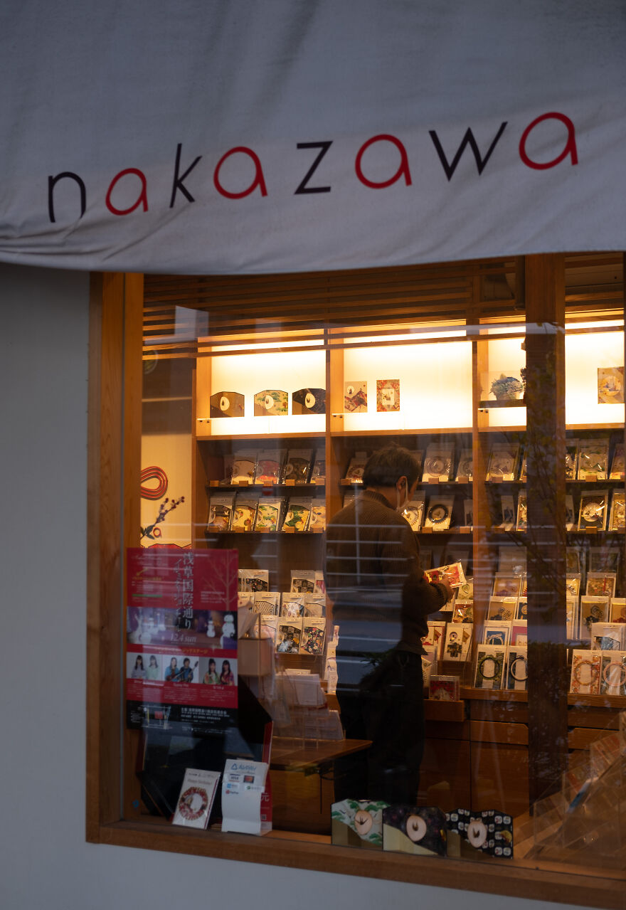 Peeking Through The Glass: Shopkeeper Tends To His Wares In Tokyo