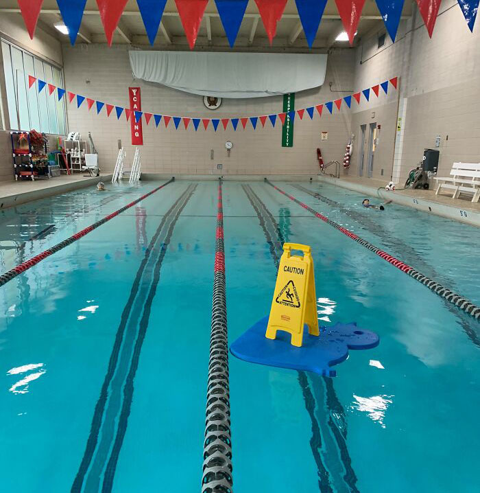 I Put A "Caution Wet Floor" Sign On Top Of A Giant Floaty Mat For April Fools. Swimmers And Colleagues Got A Kick Out Of It