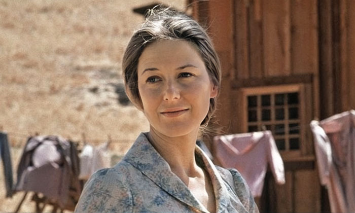 Caroline Ingalls is outside and washed clothes hang on the rope in the background