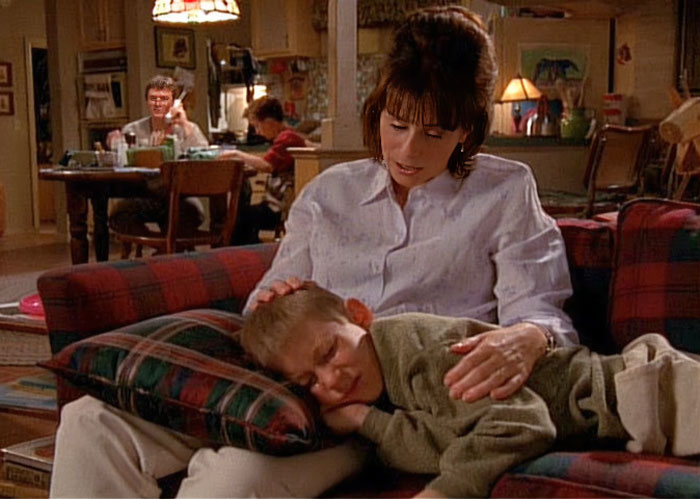 Lois Wilkerson is sitting on a red sofa, and Dewey lies down on her lap and cries