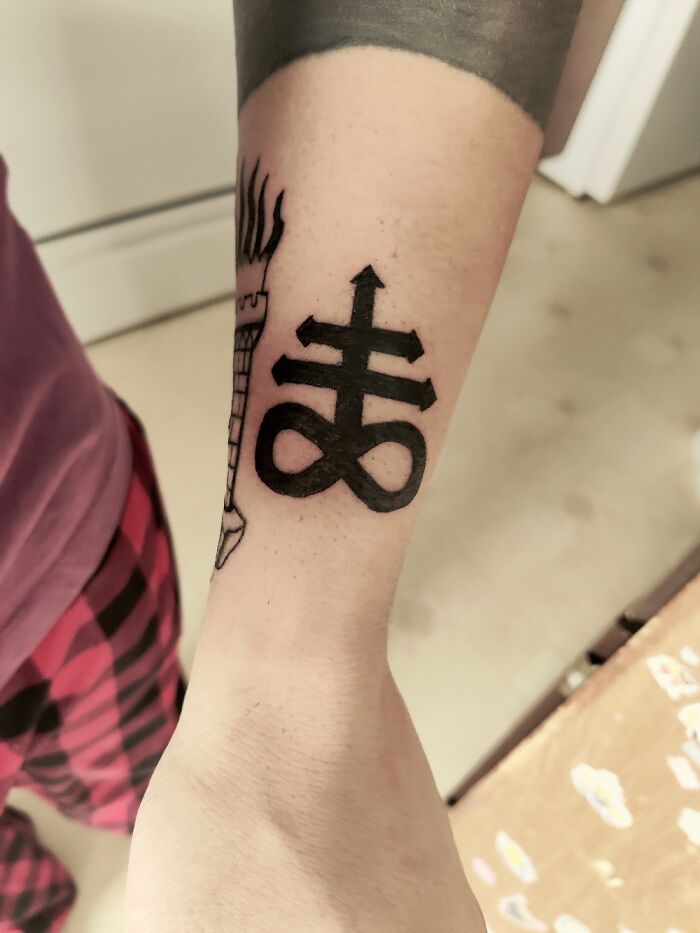 Tattoo of a unique design on a person's forearm featuring bold black lines.