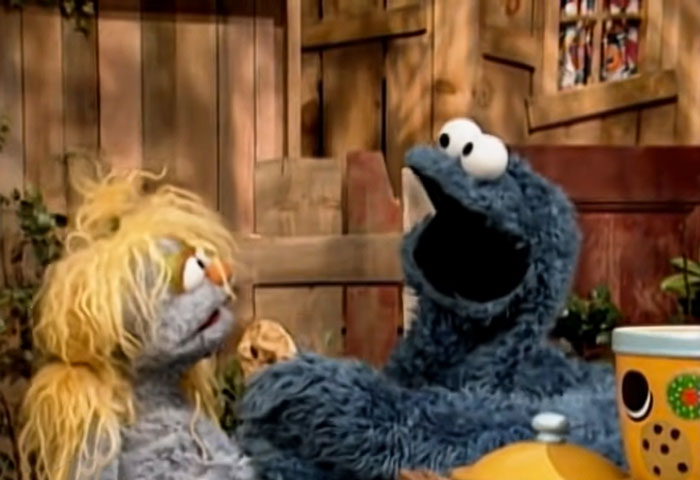 Cookie Monster giving a cookie to a girl