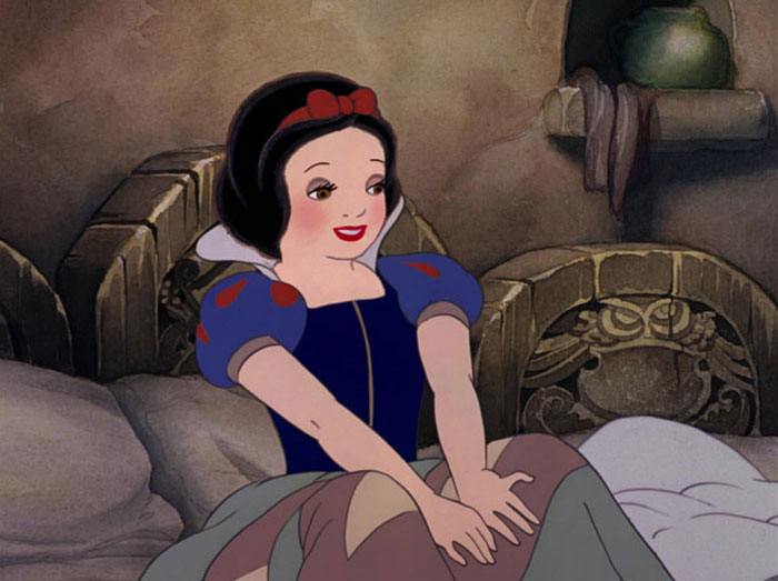 Snow White looking happy while sitting on a bed