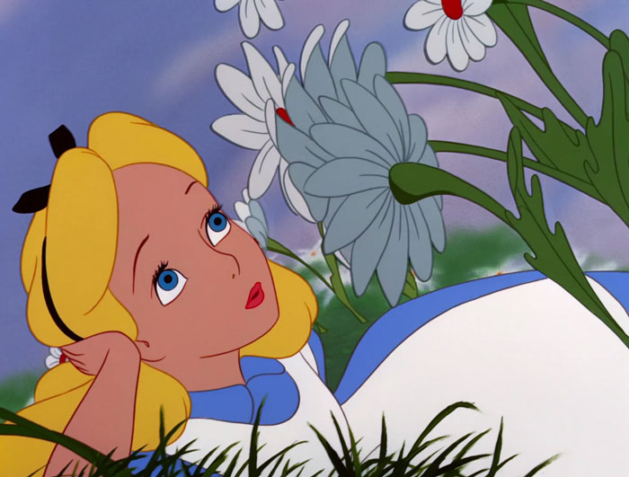 Alice lying in the meadow and dreamily looking at flowers
