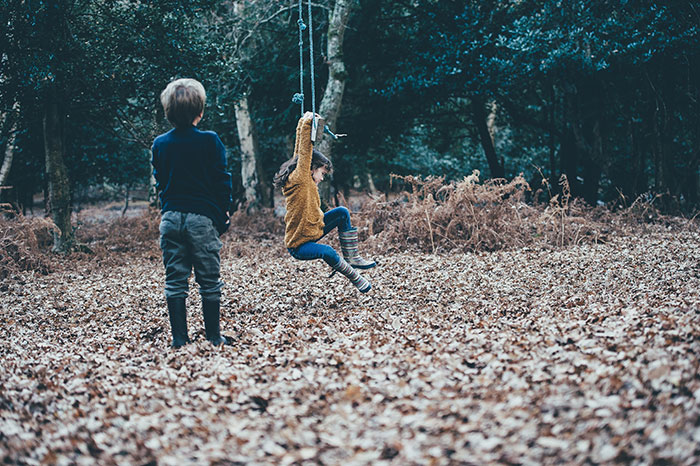 Children playing with swing on dried leaves